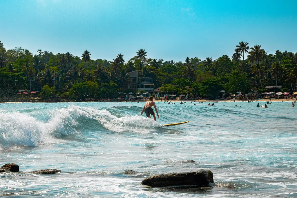 A surfer on a wave at Hiriketiya Beach, a beautiful location that is one of the Top 10 Must-Visit Beaches in Sri Lanka