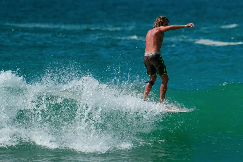 A man surfs on a clear turquoise wave at Hiriketiya Beach, a perfect experience for Sri Lanka adventure travel.