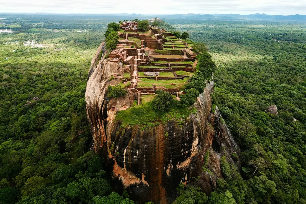 An aerial view of Sigiriya, the ancient rock fortress also known as Lion Rock, surrounded by a lush green forest in Sri Lanka